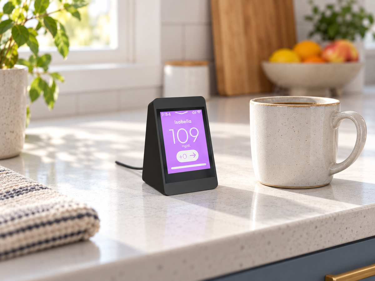 SugarHalo Mini with a purple glucose screen on a kitchen counter beside a coffee mug